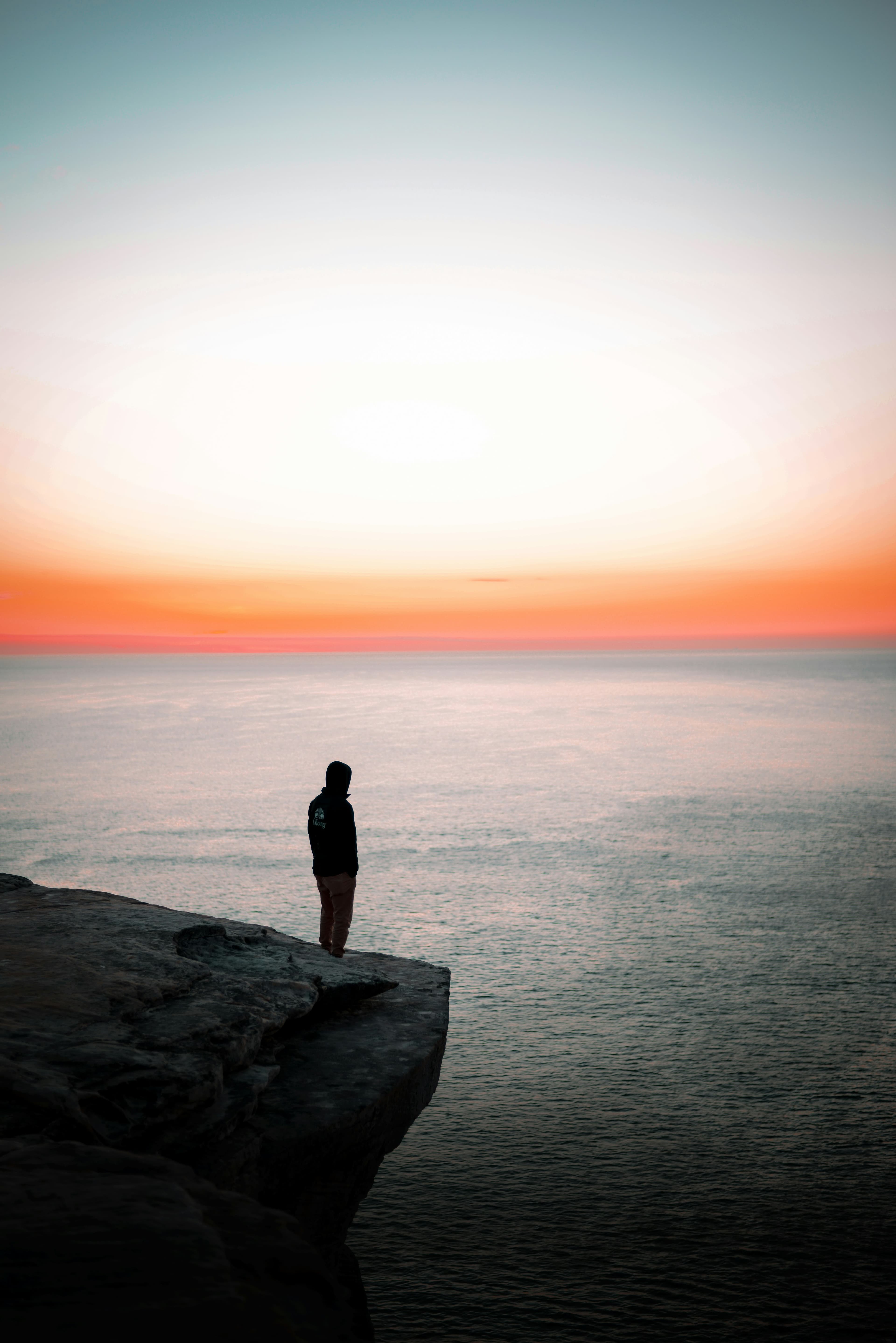 A person standing on a cliff at sunset