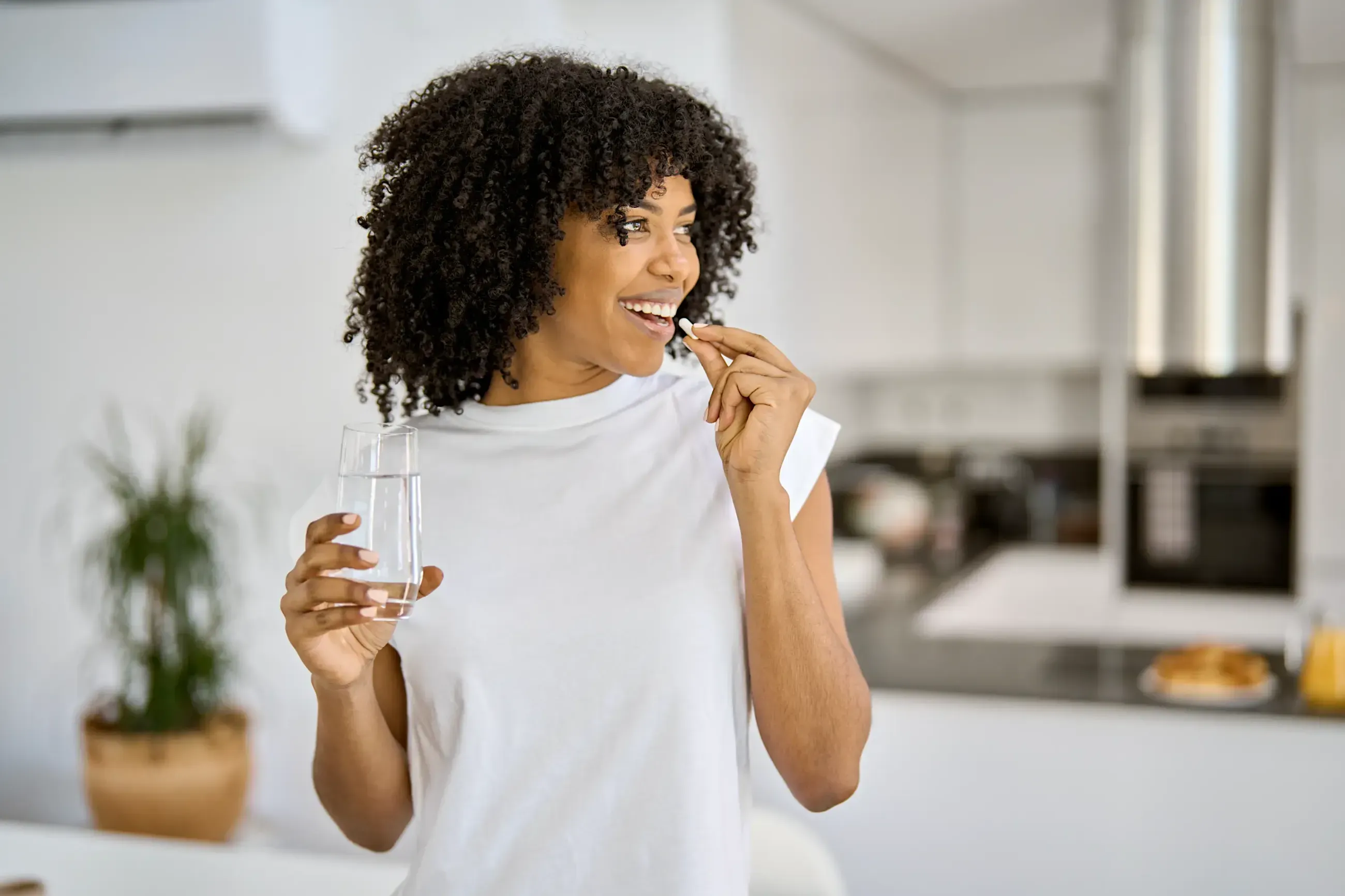 A woman holding a glass of water, smiling toward the moment